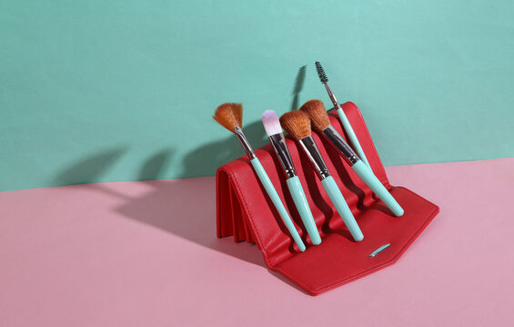 Beauty and fashion minimalistic scene. Makeup brushes and purse on blue pink pastel background with trendy shadows. Creative layout