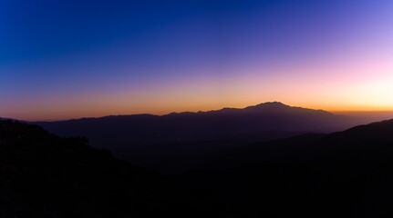 Obraz premium Wide shot of hills silhouette at sunset colorful, blue, orange and purple sky in joshua tree in america