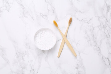 Eco-friendly bamboo toothbrushes and tooth-powder on marble background. Top view.