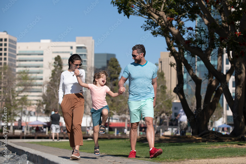 Wall mural parents with son walking in the city. family taking a walk on street outdoors against city landscape