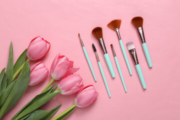 Obraz na płótnie Canvas Make-up brushes and pink tulips on pink background. Romantic, beauty concept