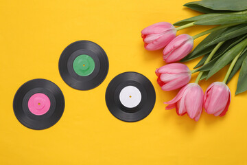 Pink tulips and vinyl records on yellow background. Romantic, music, love concept. Flat lay
