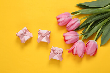 Gift boxes and pink tulips on yellow background. Romantic, holiday concept