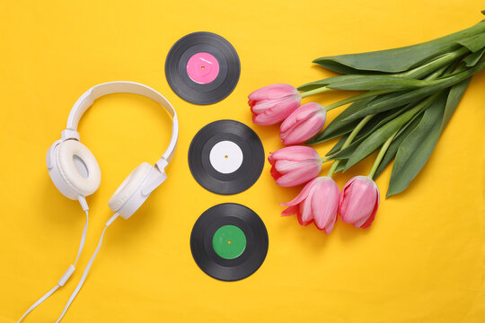Pink tulips with headphones and vinyl record on yellow background. Romantic, music, love concept. Flat lay