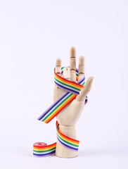 Wooden hand wrapped in a red ribbon on white background. LGBT community