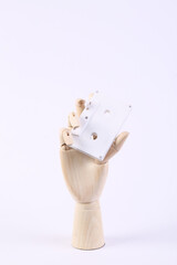 Wooden hand holding audio cassette on white background