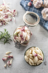Top view jar full of garlic cloves, a bowl full of lovely peeled garlic cloves and savory rosemary