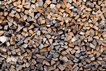 Large pile of firewood, cut of wood, dark texture group of objects