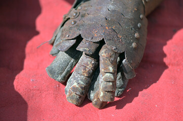 The hand of a rusty knight armor on a red background. 