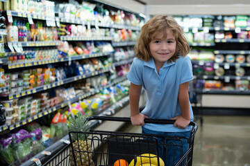 Child with shopping cart at grocery store or supermarket. Purchases, sale consumerism in store....