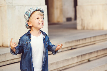 Childhood lifestyle concept. Kid wearing denim jacket and hat. Fashionable little boy on a walk in city.