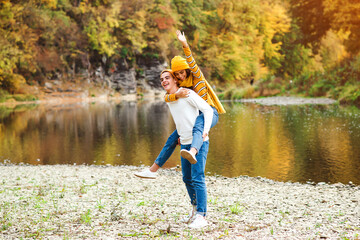 Fototapeta na wymiar Young people walking near lake in autumn. Fashion, lifestyle and autumn vacation. Stylish man and woman on a walk.