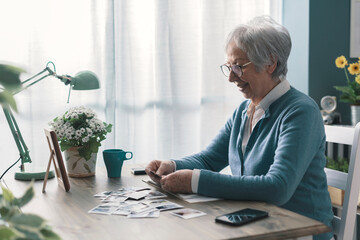 Happy senior lady going through old pictures