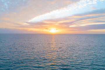 Obraz premium Calm sea with sunset sky and sun through the clouds over. Ocean and sky background, seascape.