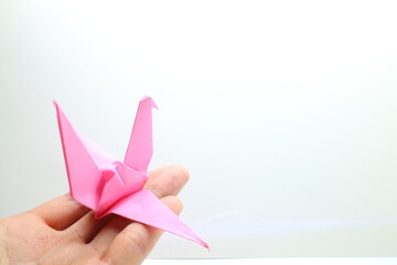 手のひらにのせるピンク色の折鶴