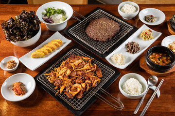 hanu bulgogi and pork Bulgogi with rolled eggs, rice, kimchi , salad , tofu soup on a table