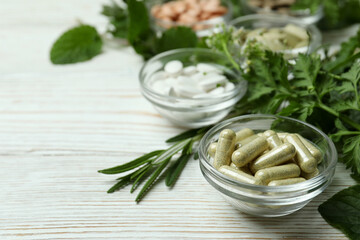 Concept of herbal medicine pills on white wooden table, space for text