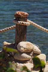 Drewniany słupek obwiązany białą liną na tle morza