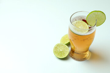 Glass of beer with lime on white background