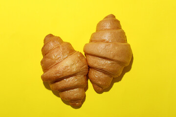 Tasty croissants on yellow background, top view