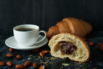 Concept of tasty breakfast with croissant with chocolate on dark background