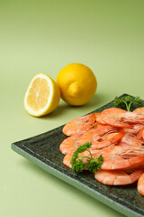Plate with tasty shrimps on green background