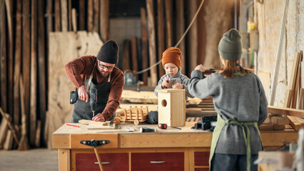 Parents and kid making  wooden bird house in craft workplace