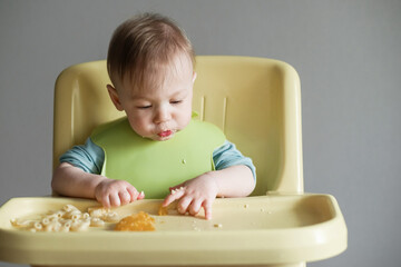 little child eats on gray background