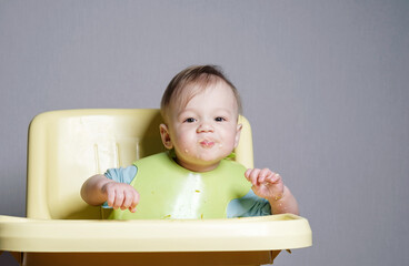 little child eats on gray background, child testing food