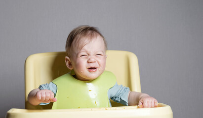 little child eats on gray background, child testing food, funny face