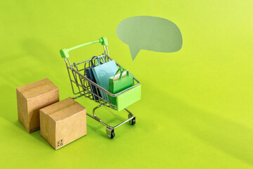 Cardboard boxes or paper boxes in shopping cart on green background. Online shopping and delivery service concept.