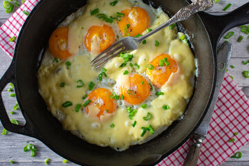 Fried eggs sunny side up with cheese in a pan