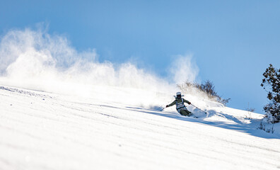 Skier rides on fresh snow against blue sky