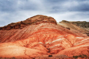 The hill is red yellow and white clay, ancient multi-colored deposits. Geology, erosion, soil layers. View of the Altyn-Emel park in Kazakhstan