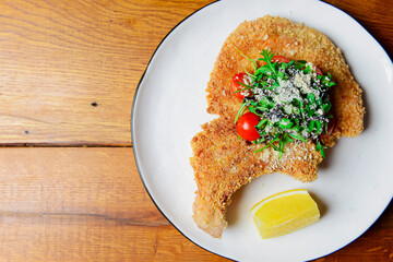 One deep fried fish bone steak with cherry tomatoes and fresh arugula on top.