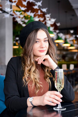 Attractive young woman with a drink in restaurant. Caucasian woman sitting in restaurant and drinking champagne.
