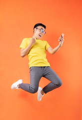 Fototapeta na wymiar Asian man in yellow t-shirt jumping on orange background
