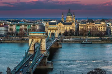 Photo sur Plexiglas Széchenyi lánchíd Budapest, Hungary - The famous Szechenyi Chain Bridge (Lanchid) at sunset decorated with national flags celebrating the 15th of March 1848 civic revolution day. St.Stephen's Basilica at background