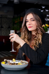 A platter of fresh organic oysters on ice at restaurant. Attractive young woman with a drink in restaurant.