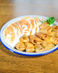 Close up of french style crepes with souffle whipped cream served on a plate over rustic wooden table background.