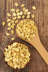 Roasted fava beans for a healthy vegan snack food in a wooden bowl and spoon on rustic wood background. Highly nutritious being high in protein, vitamins, dietary fibre and nutrients. Top view.