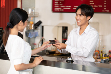 male receptionist or hotel front desk smiling and receiving credit card from woman guest