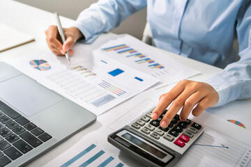 Woman accountant use calculator and computer with holding pen on desk in office. finance and...