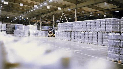 loader on the background of a huge industrial food warehouse with plastic PET bottles with beer,  water,  drinks.