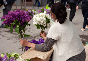 Two bouquets of lilacs in the hands of a woman saleswoman at the market