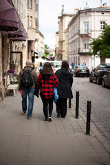 The daughter in a checkered shirt walks between her parents on the street of the old town
