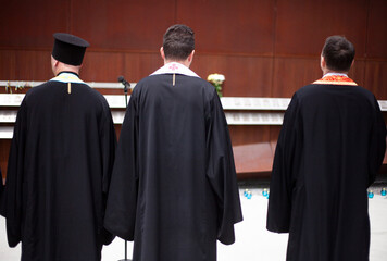 Three priests in robes near the memorial on Remembrance Day