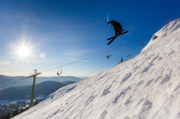 Black skier jumps off a cliff in winter