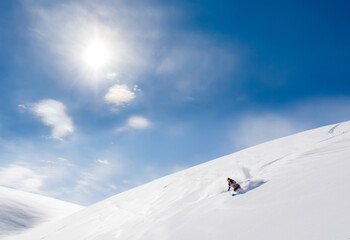 Skier rides on fresh snow against blue sky