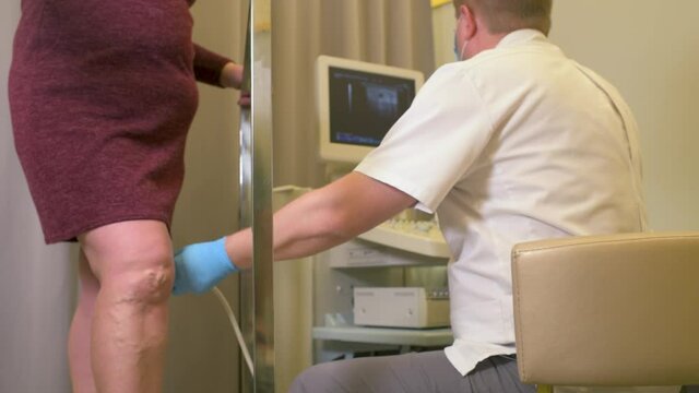a vascular surgeon or phlebologist makes an ultrasound of varicose veins on the legs of a female patient.